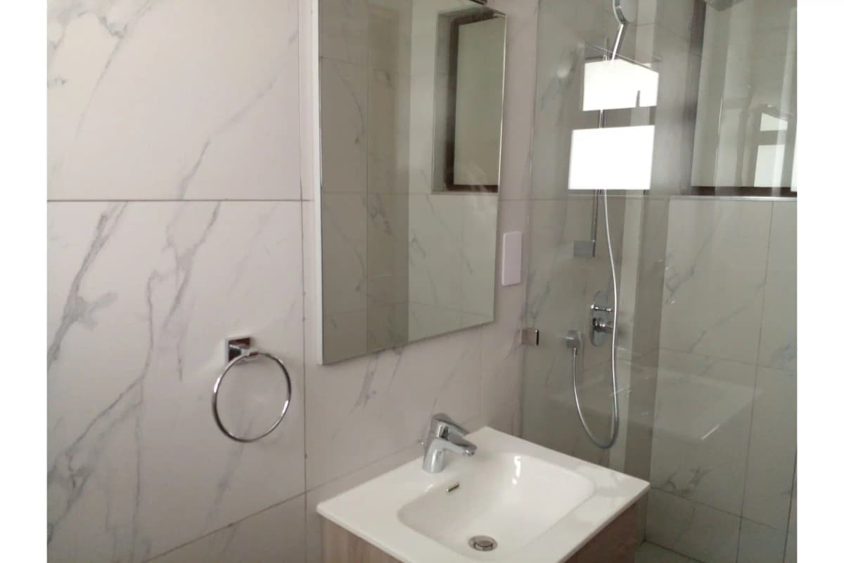 Modern bathroom with marble tiles, walk-in shower, and vanity