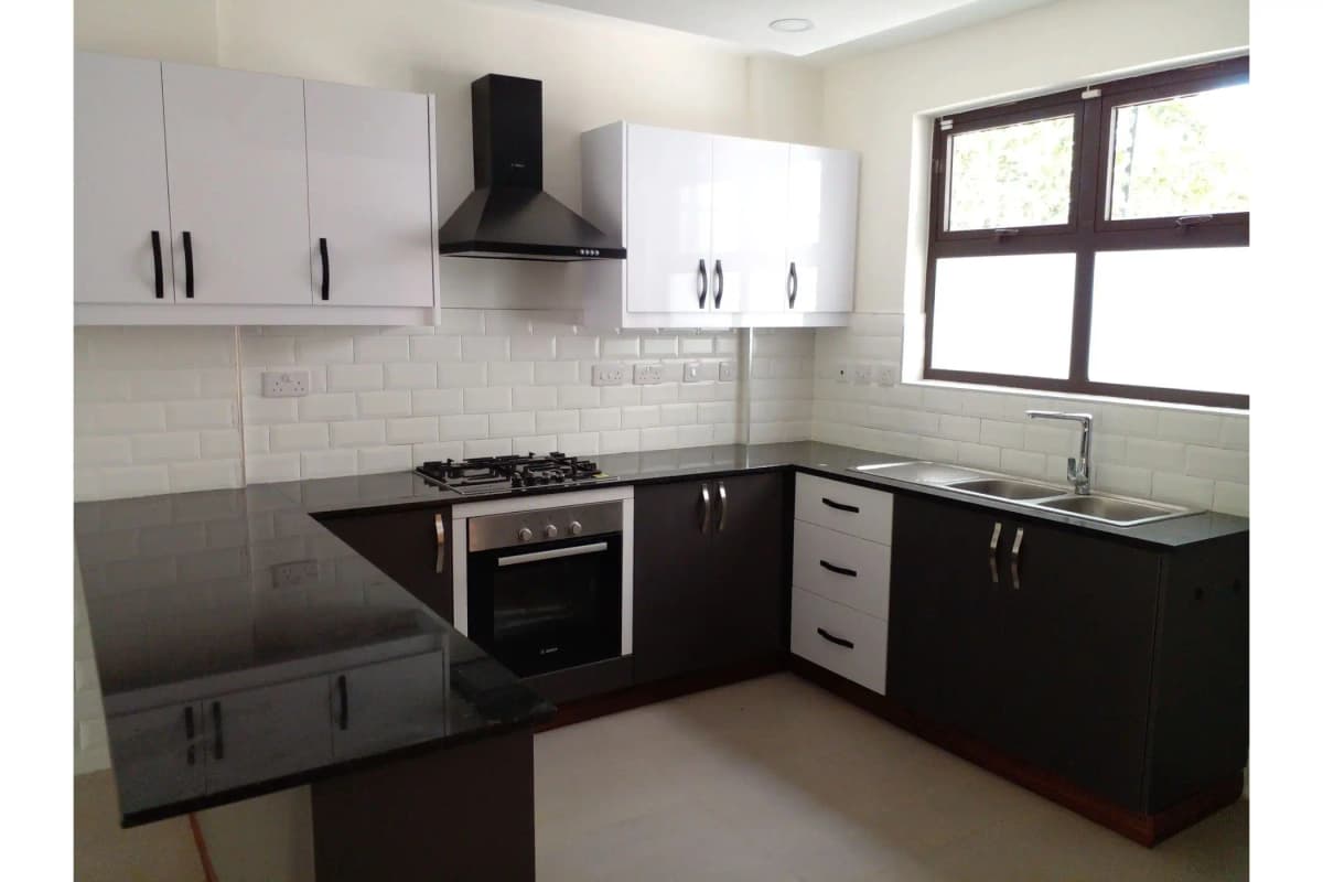 Modern kitchen with black and white cabinetry, gas cooktop, hood