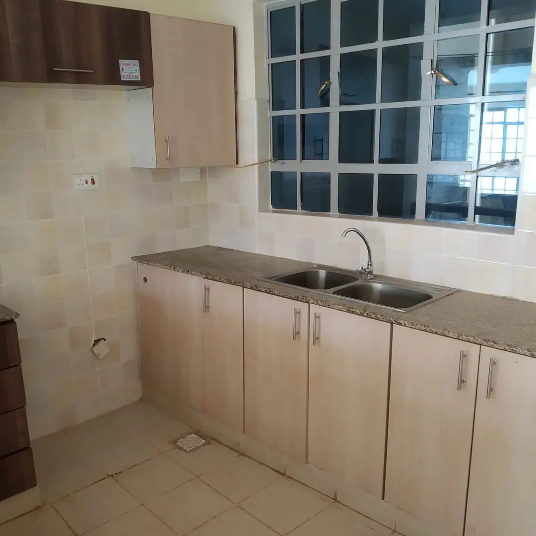 Compact kitchen with cream cabinetry and stainless steel sink