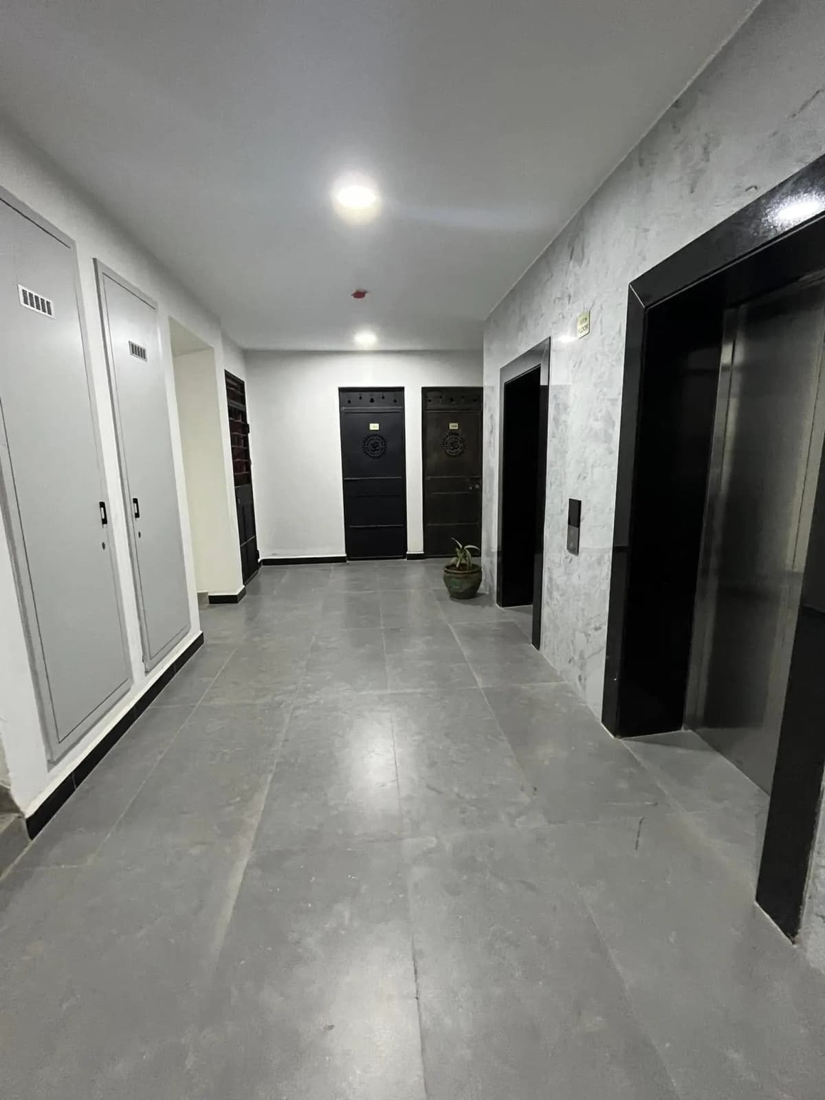 Modern building corridor with polished concrete floors and black doors