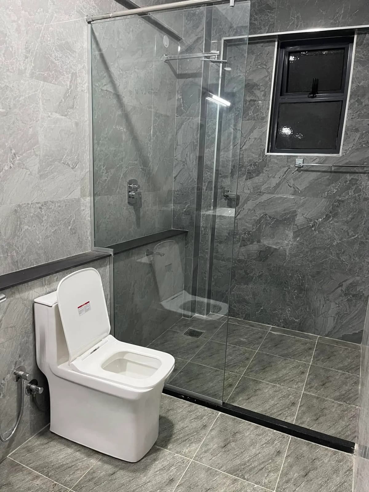 Modern bathroom with grey tile, walk-in shower, white toilet