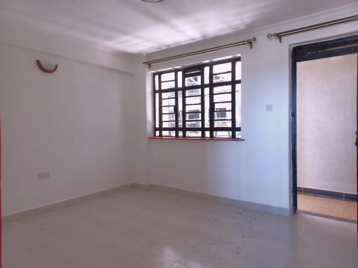 Empty living room with barred window and polished concrete floor