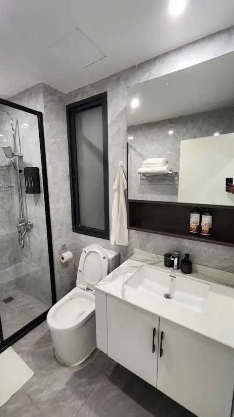 Modern bathroom with gray marble tiles, white vanity, and glass shower