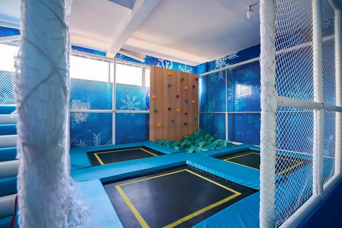 Indoor trampoline park with blue flooring and safety netting