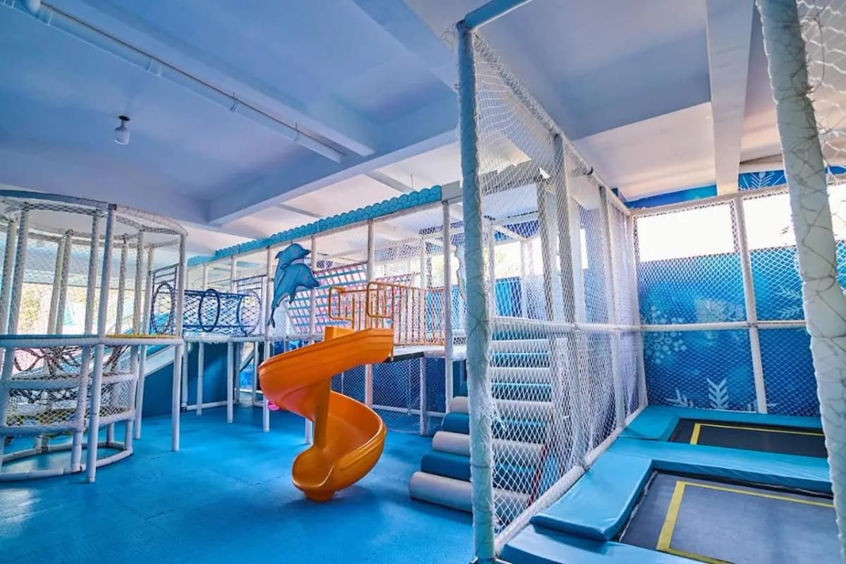 Indoor play area with slides, trampolines, and safety netting