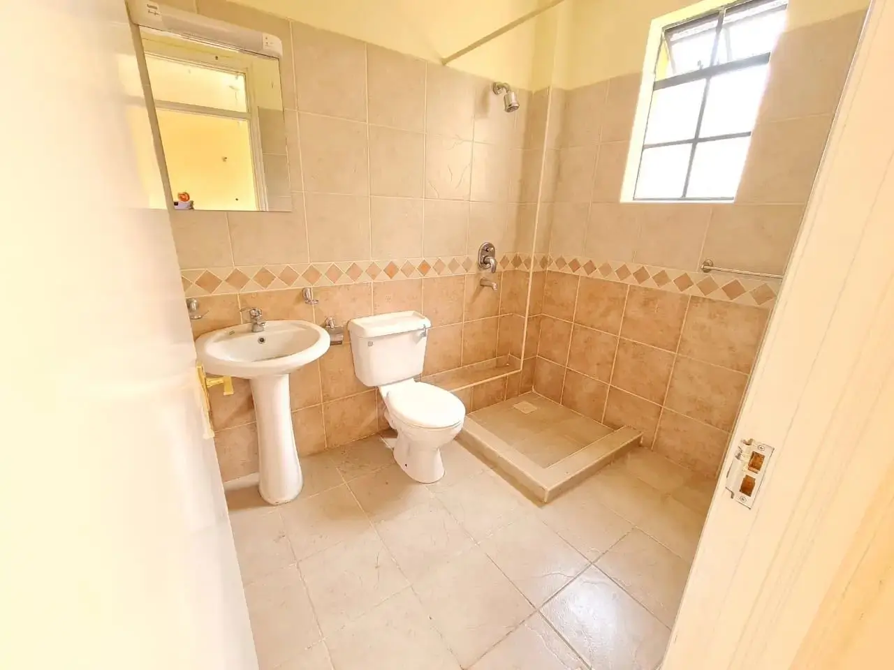 Spacious bathroom with pedestal sink, toilet, and walk-in shower