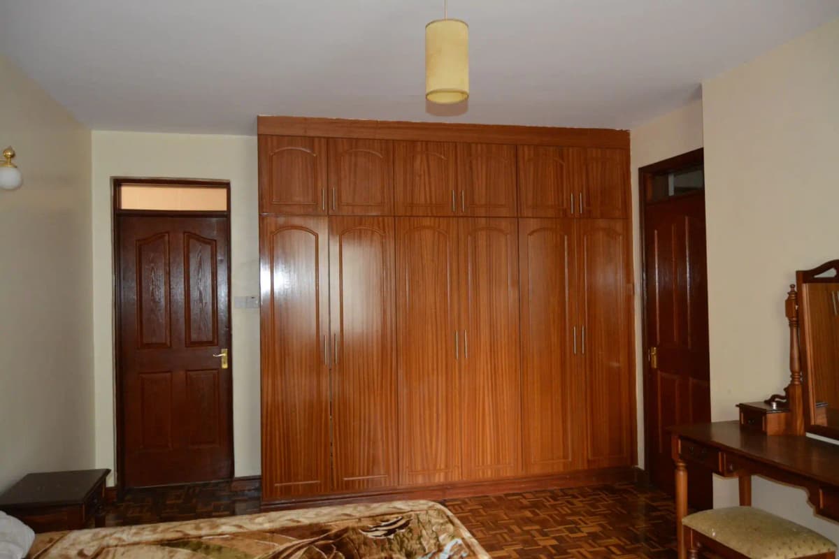 Master bedroom with large wooden wardrobe and parquet flooring