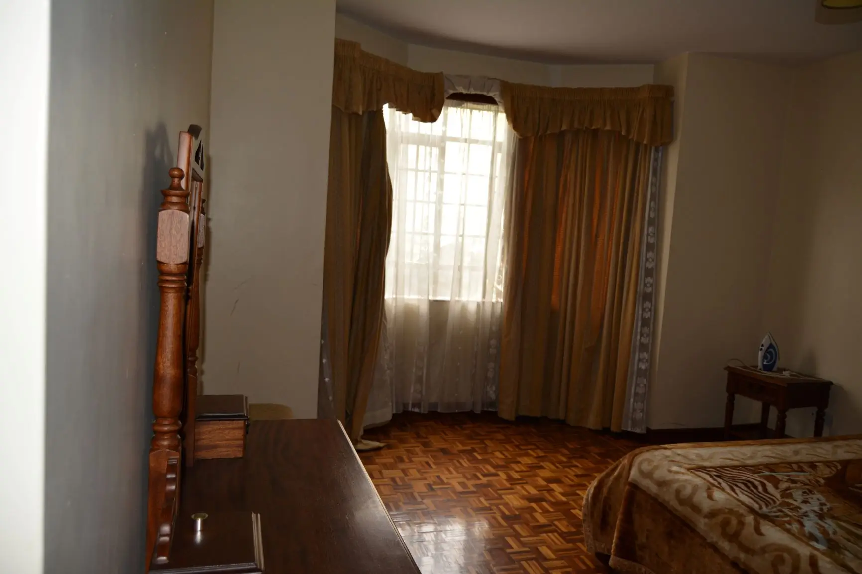 Spacious bedroom with wooden bed frame and bay windows
