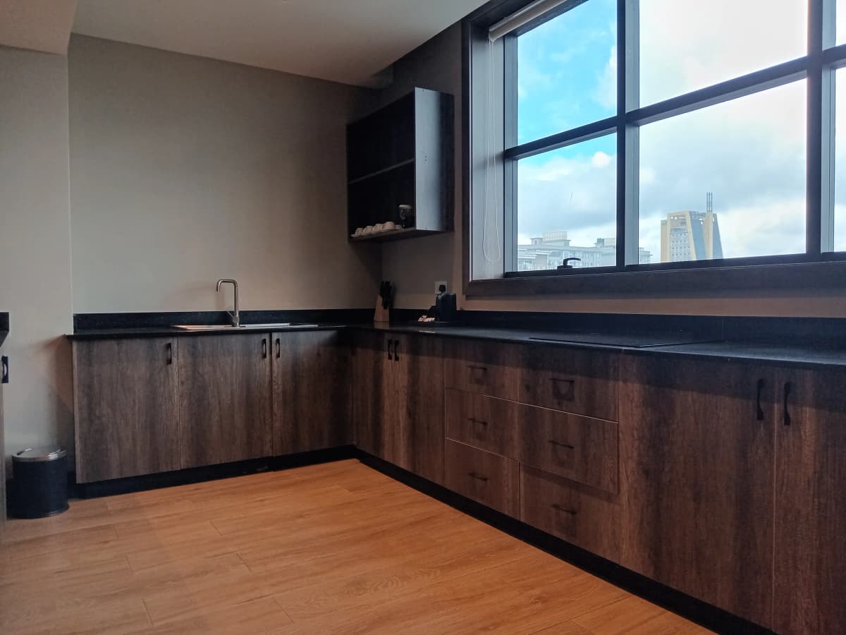 Modern kitchen with dark wood cabinetry, black countertops, city skyline views