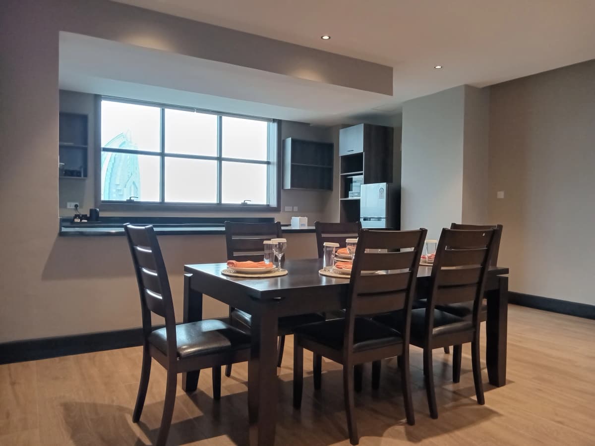Open-plan dining area with black table and kitchen visible