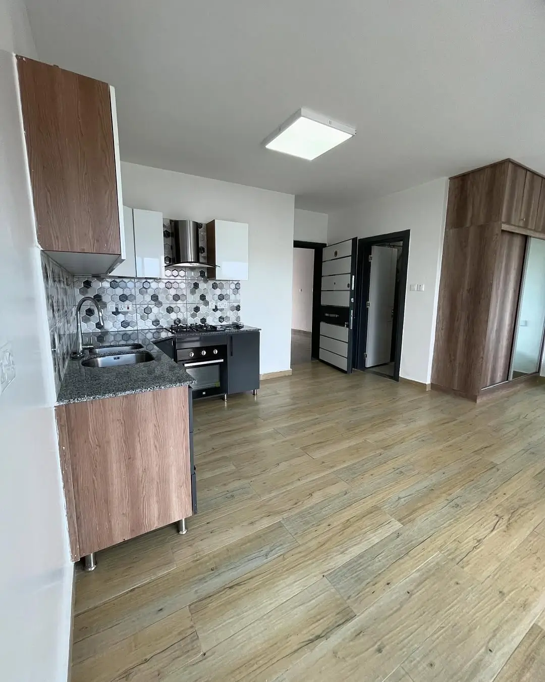Open-plan kitchen with dark cabinetry and patterned backsplash