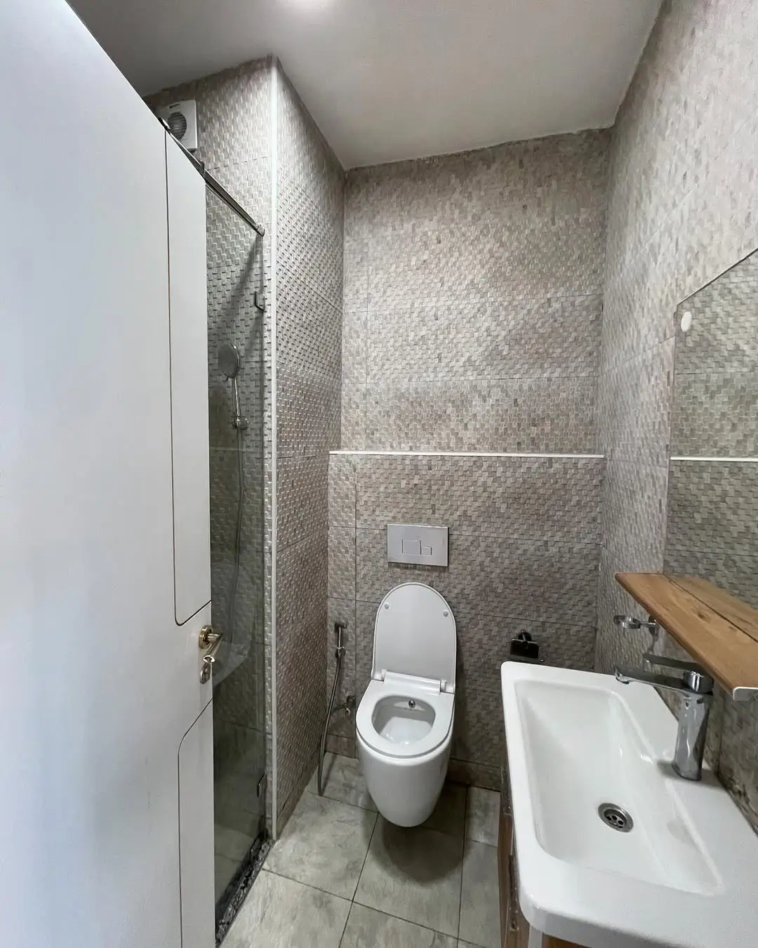 Compact bathroom with toilet, sink, and walk-in shower