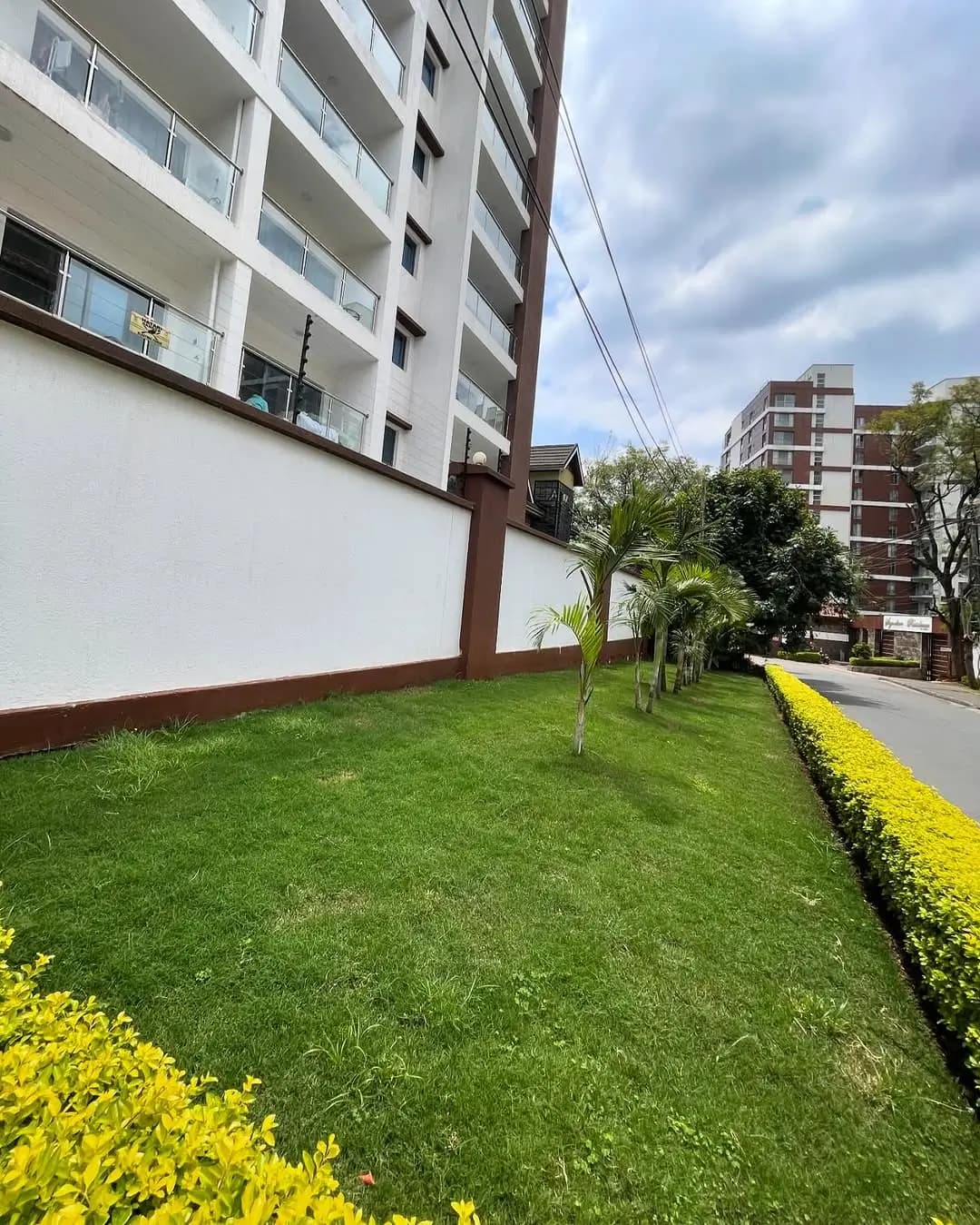 Well-manicured compound grounds with green lawn and yellow flowering border