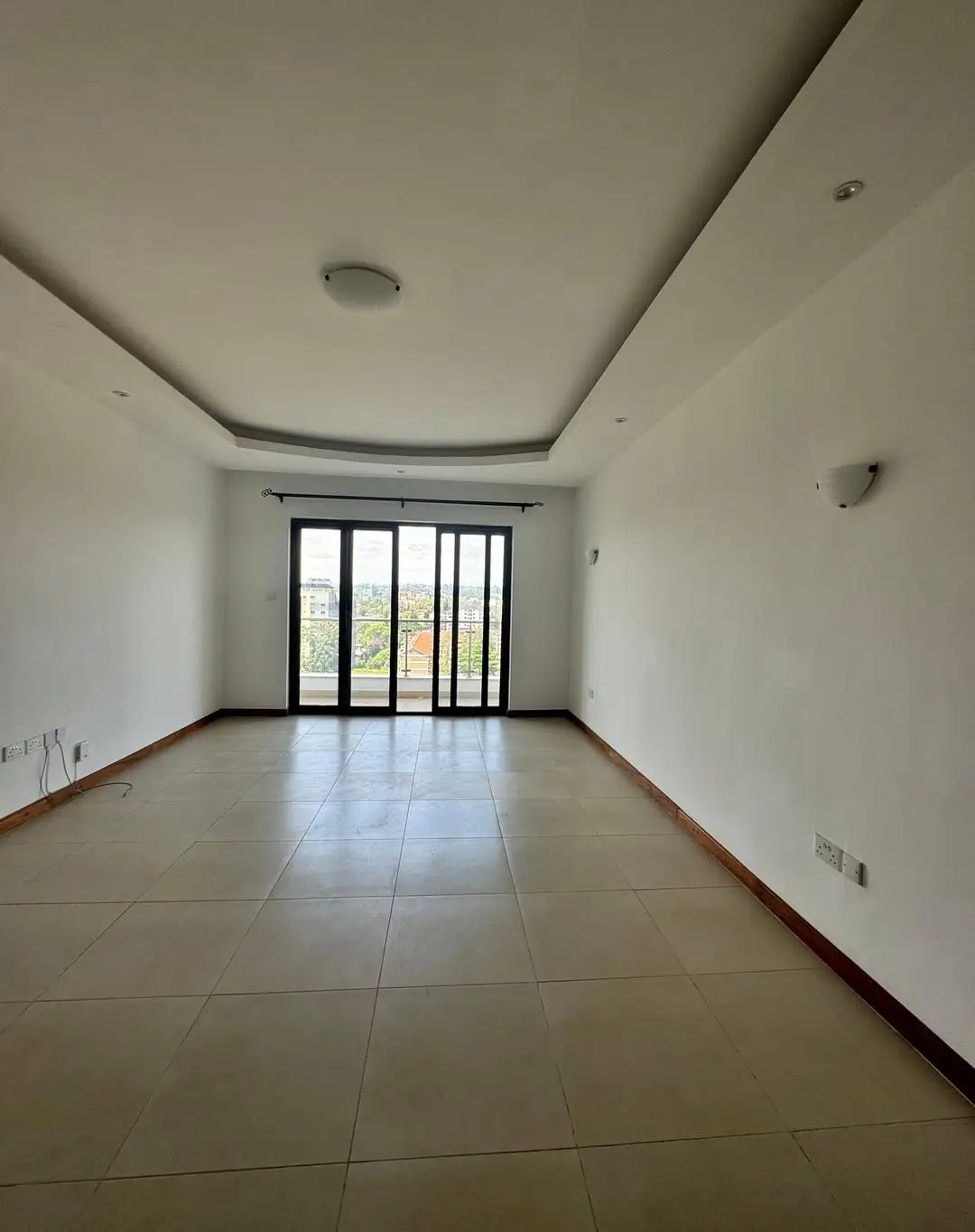 Spacious empty living room with large glass doors and polished tile floor