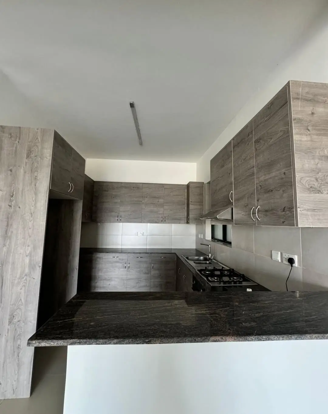 Modern kitchen with dark countertops and wood-grain cabinetry