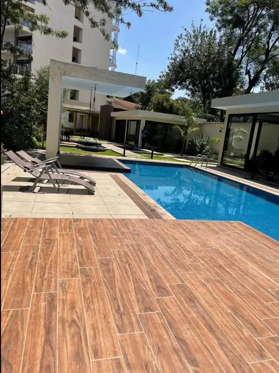 Resort-style swimming pool with wood-look decking and loungers