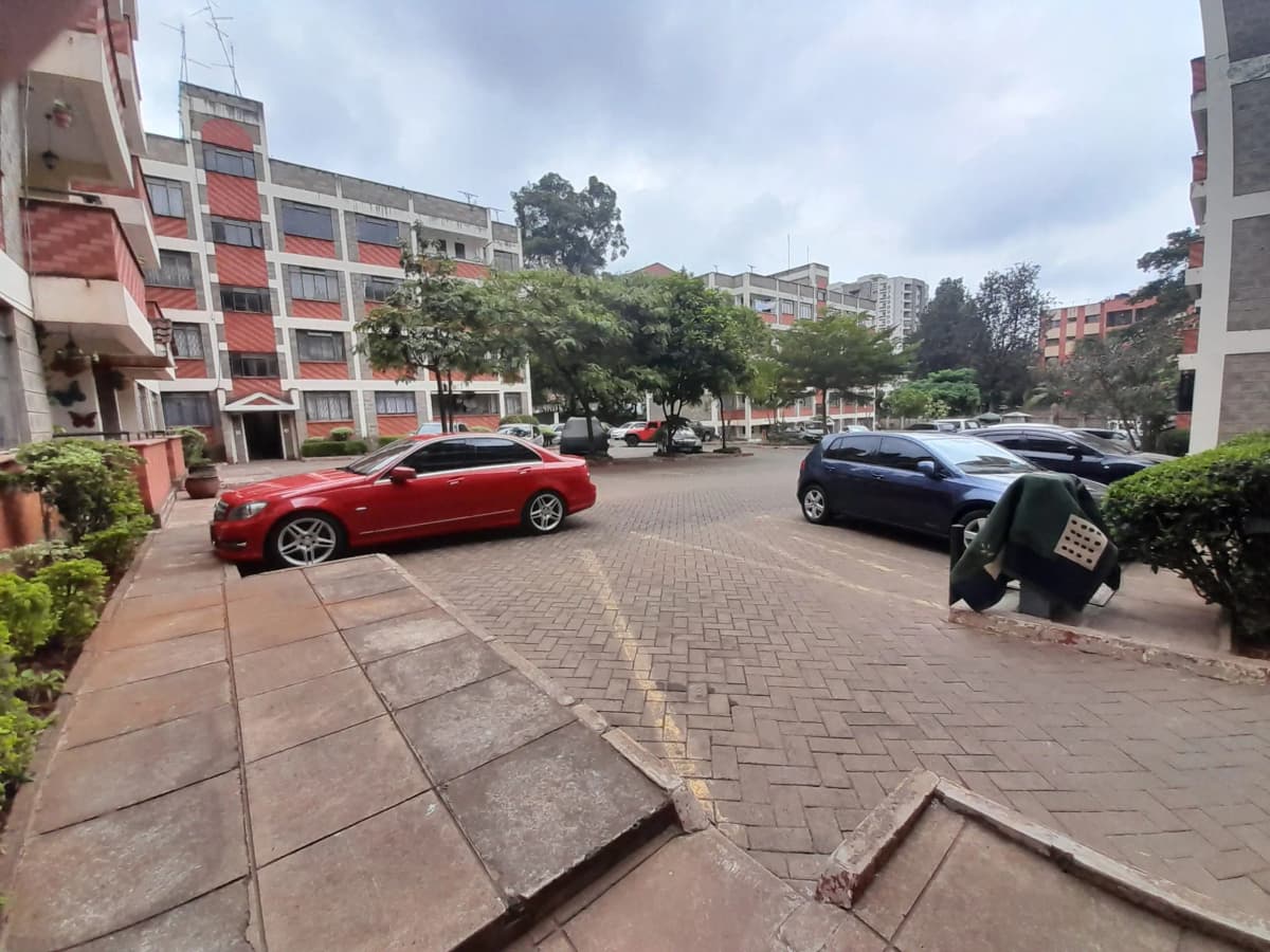 Compound parking area with multiple vehicles and residential buildings