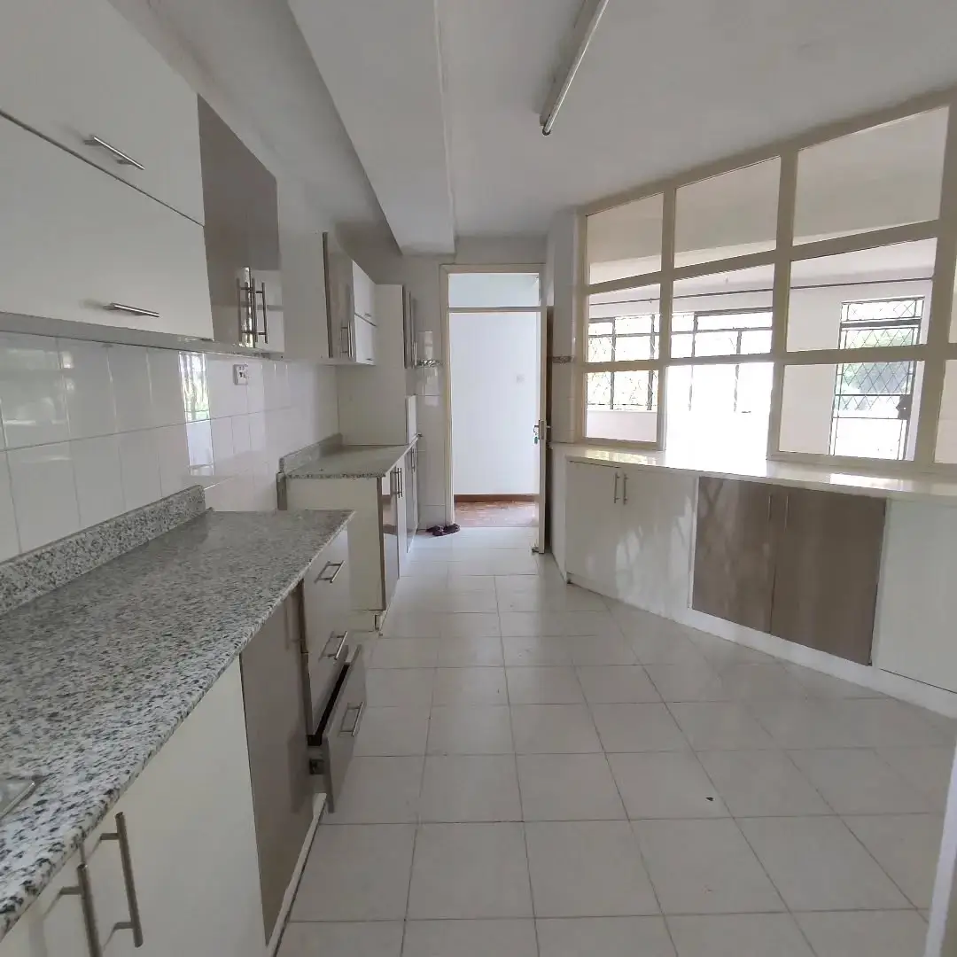 Spacious kitchen with granite counters, white cabinetry, dining area