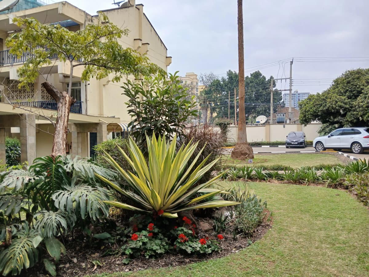 Landscaped compound grounds with mature trees and flowering plants