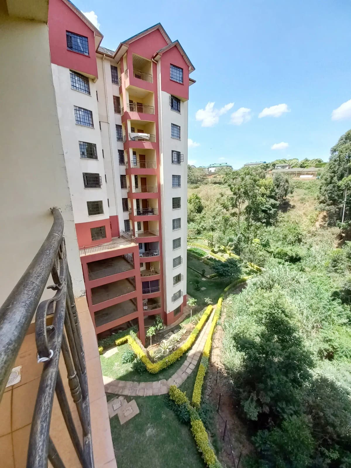 Multi-story residential building with red and white facade overlooking green valley