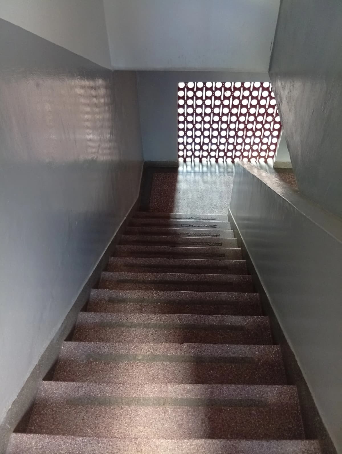Interior staircase with decorative perforated wall panels and natural light