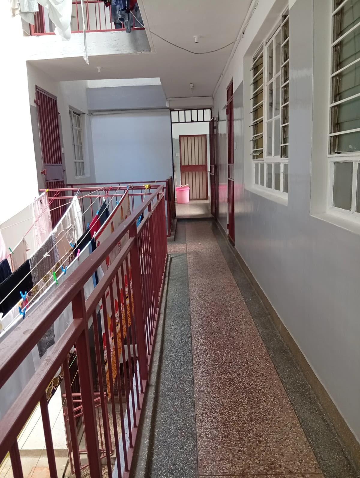 Narrow corridor with red metal railings and white storage cabinets