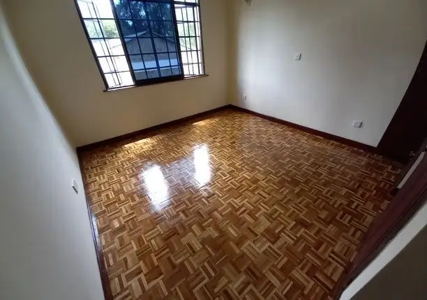 Empty bedroom with herringbone wood flooring and natural light