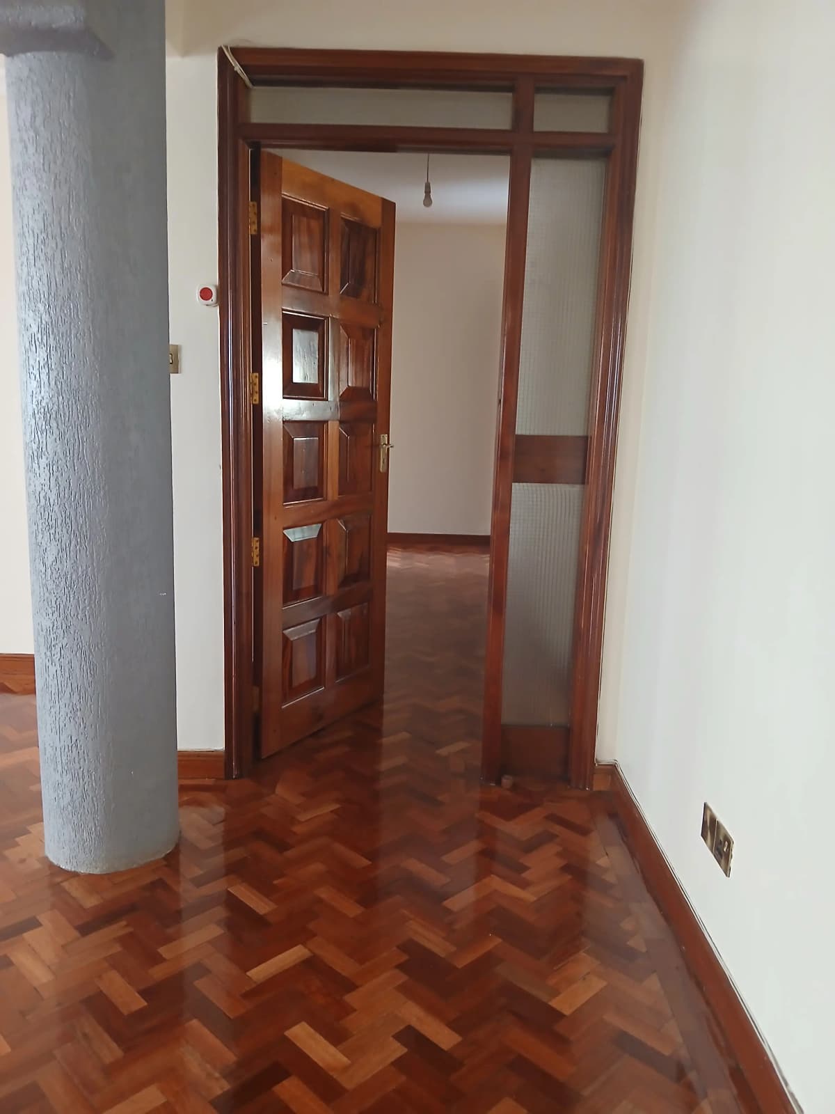 Hallway with wooden door, herringbone flooring, white walls