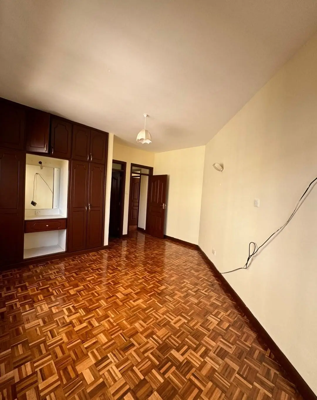 Spacious bedroom with herringbone parquet flooring and built-in wardrobe