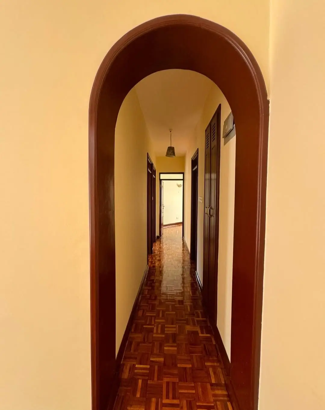 Long corridor with arched wooden doorway and herringbone flooring