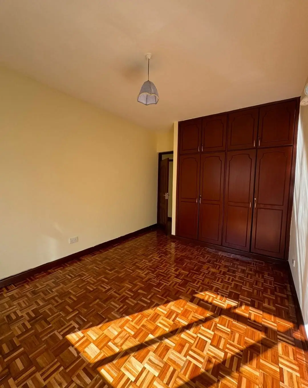 Spacious bedroom with wooden wardrobe and parquet flooring