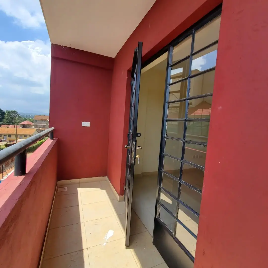 Red-walled balcony with sliding glass doors and distant city view
