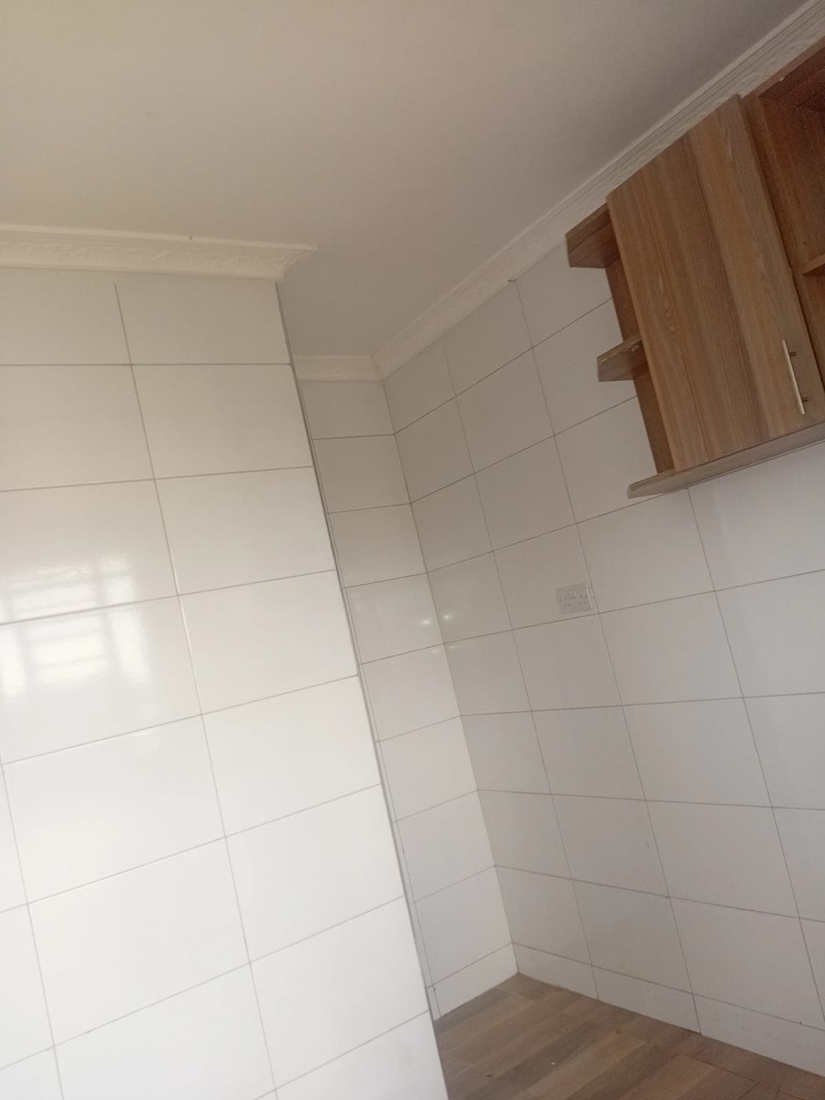 Empty bathroom with white tiles and wooden cabinet