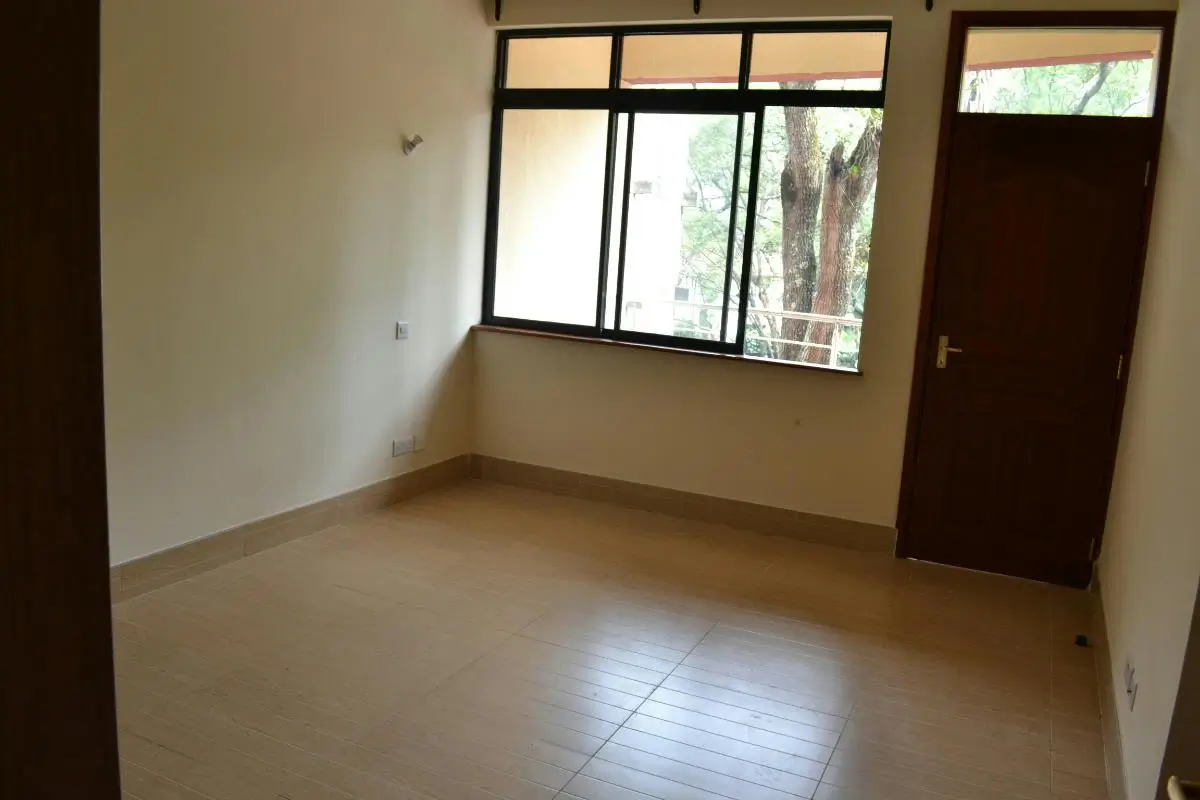 Spacious empty bedroom with large windows and wooden door