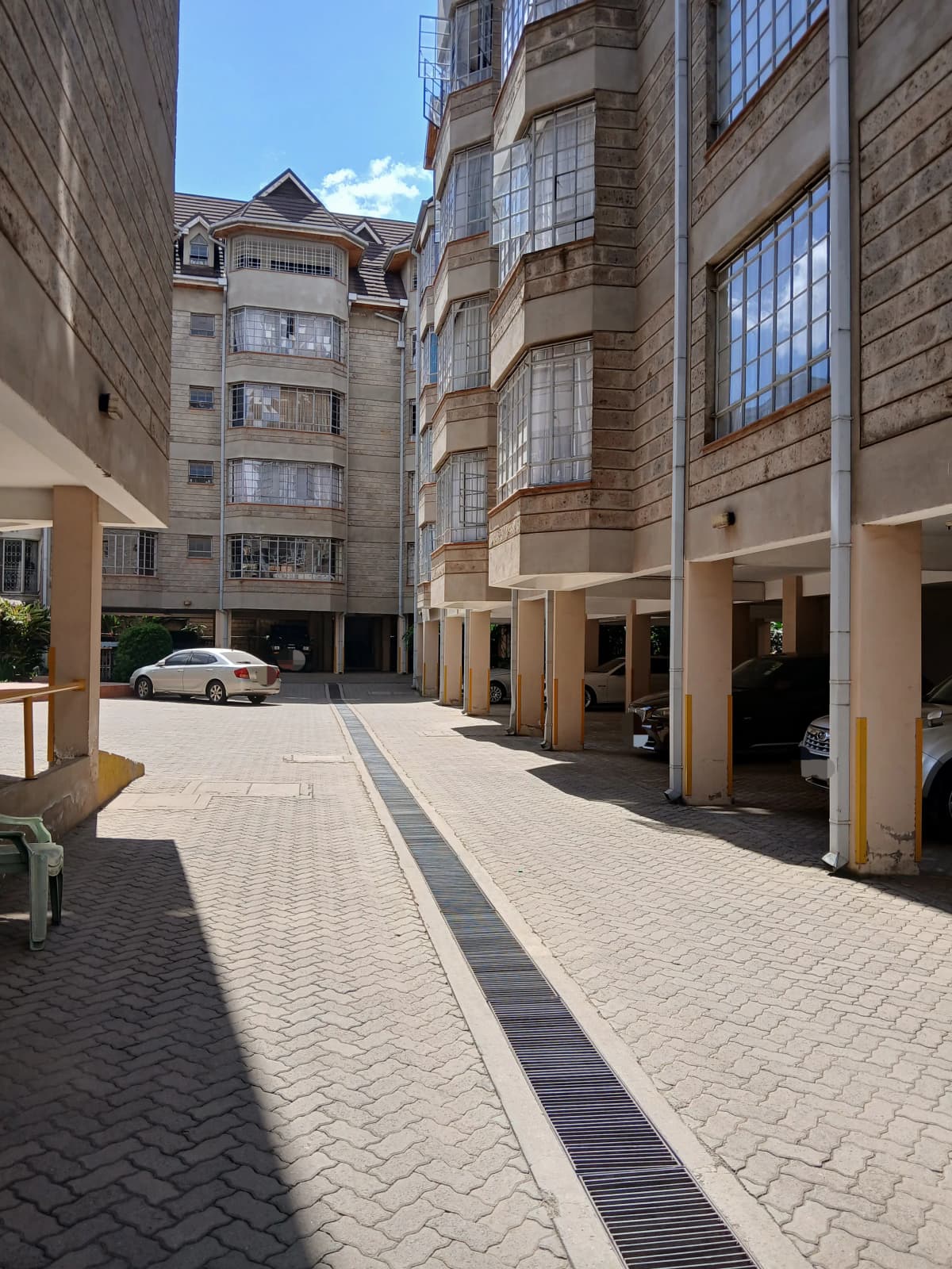Gated compound courtyard with paved walkway and parked car