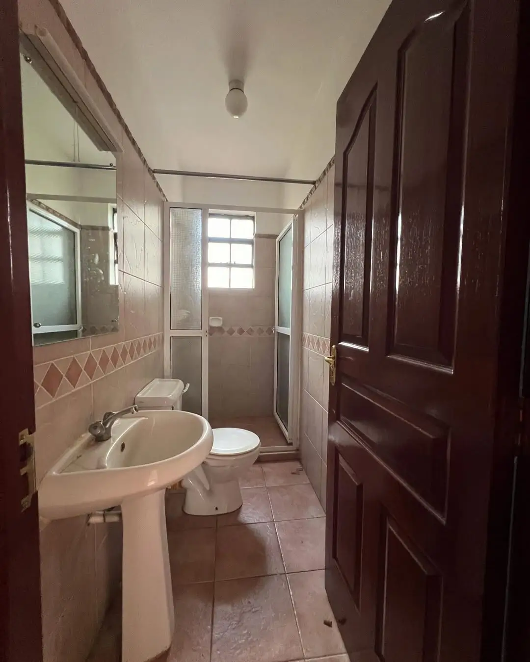 Compact bathroom with pedestal sink, toilet, and shower enclosure