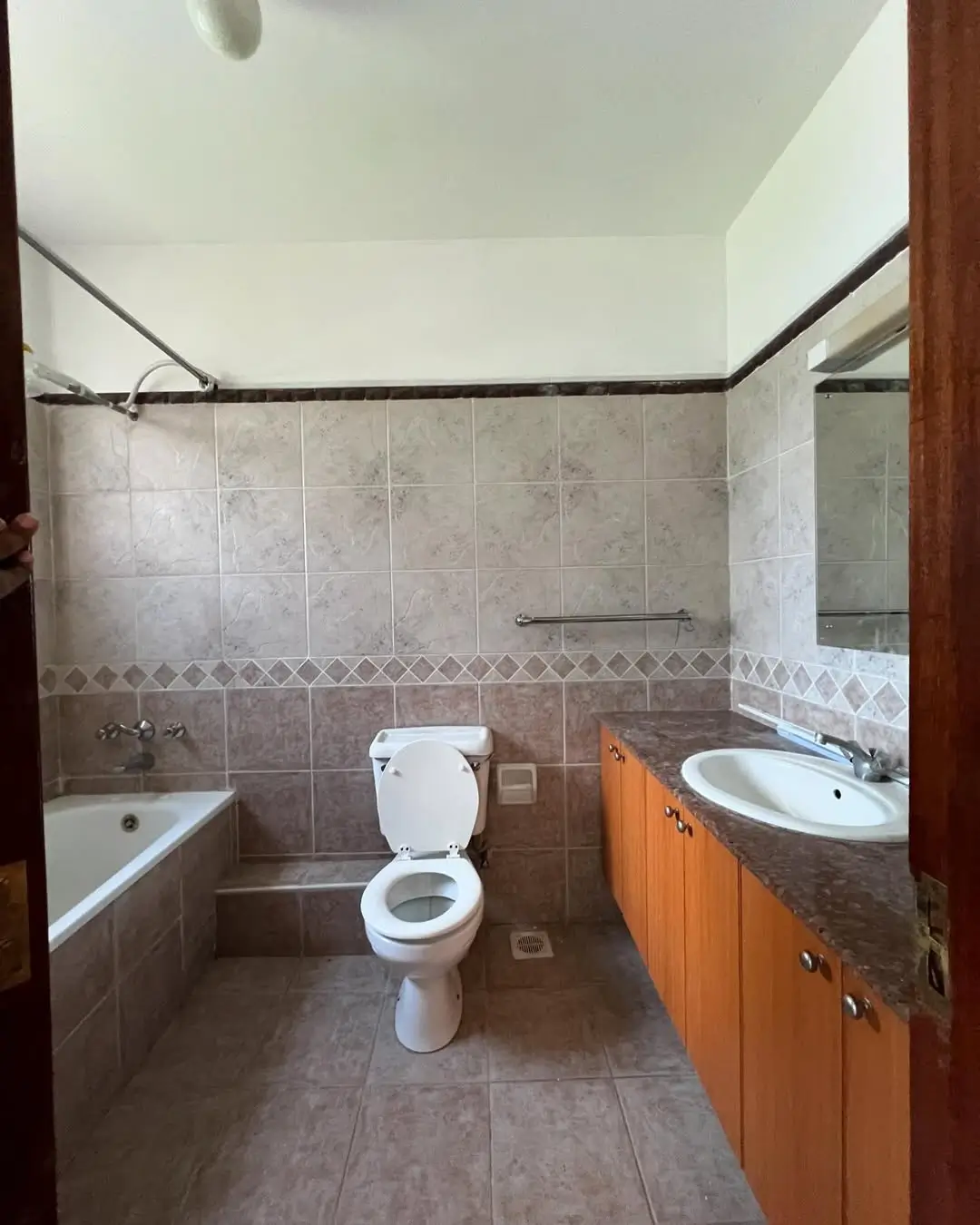 Spacious bathroom with bathtub, toilet, and wooden vanity