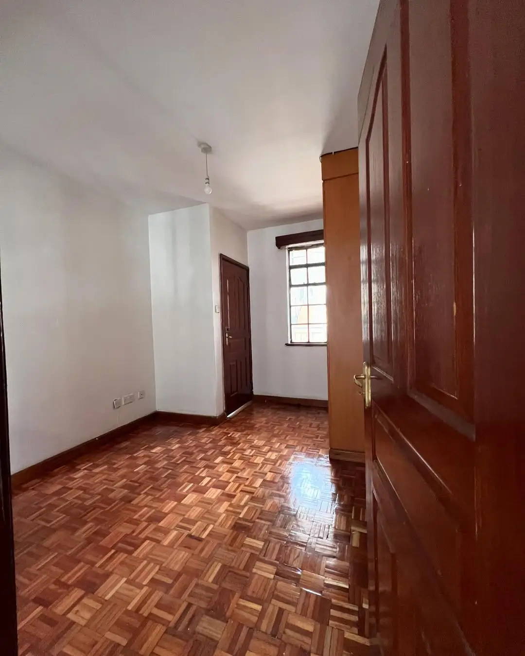 Spacious bedroom with herringbone parquet flooring and wooden wardrobe