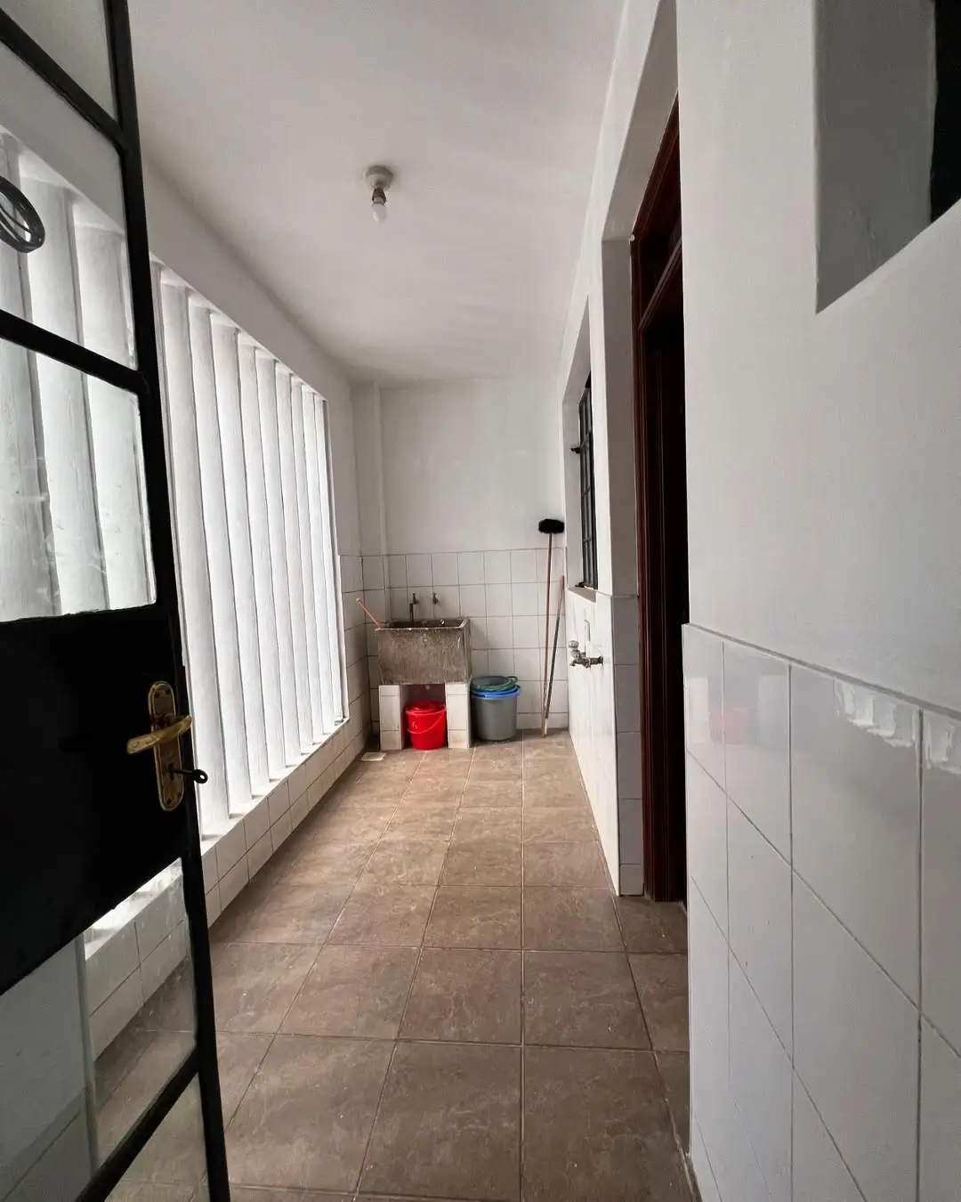 Bright laundry area with terracotta tile flooring and white walls