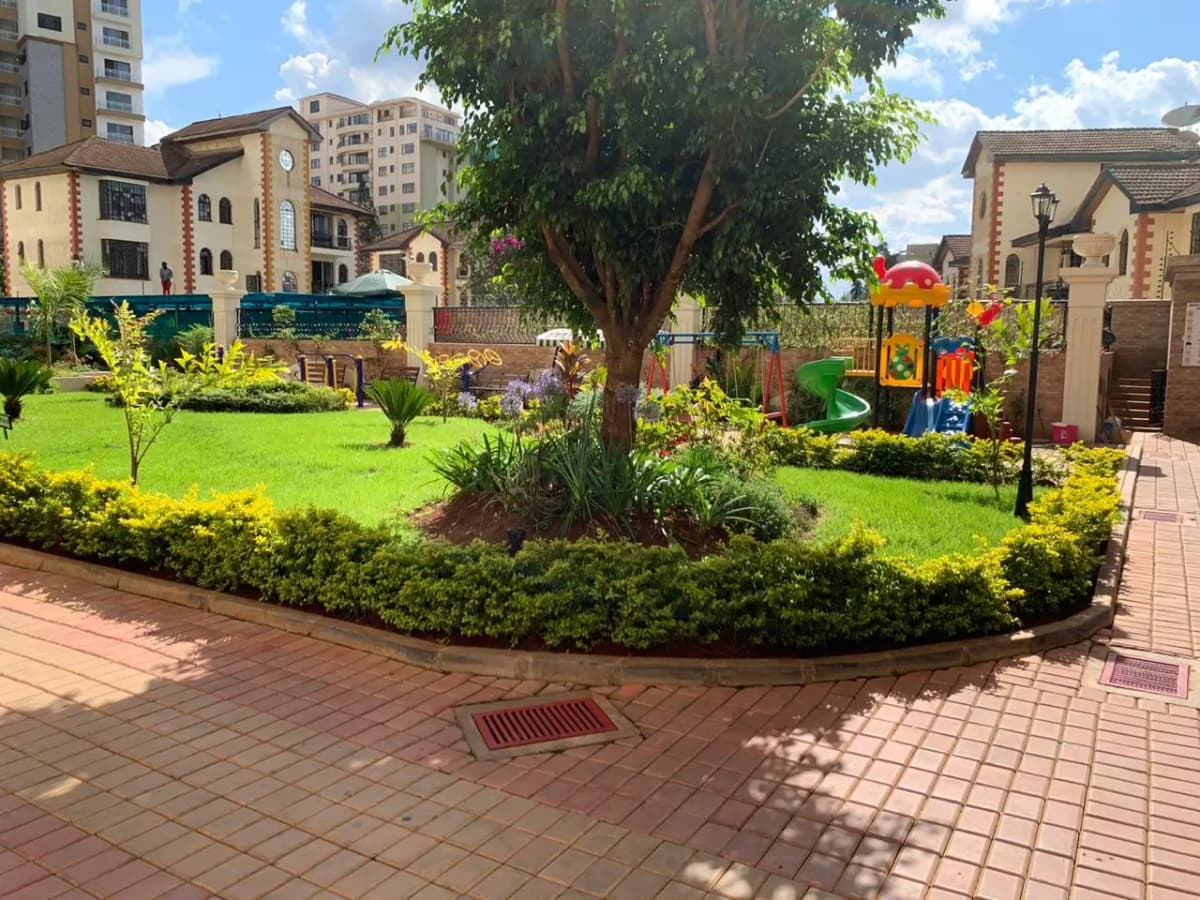 Lush compound garden with playground, manicured lawn, mature trees