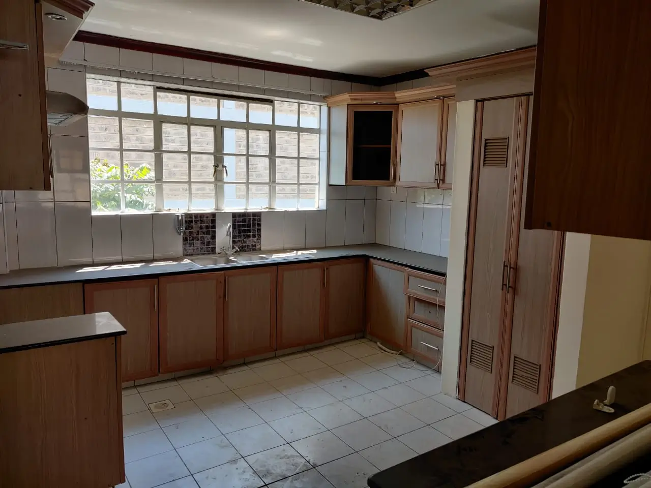 L-shaped kitchen with wooden cabinets and large window