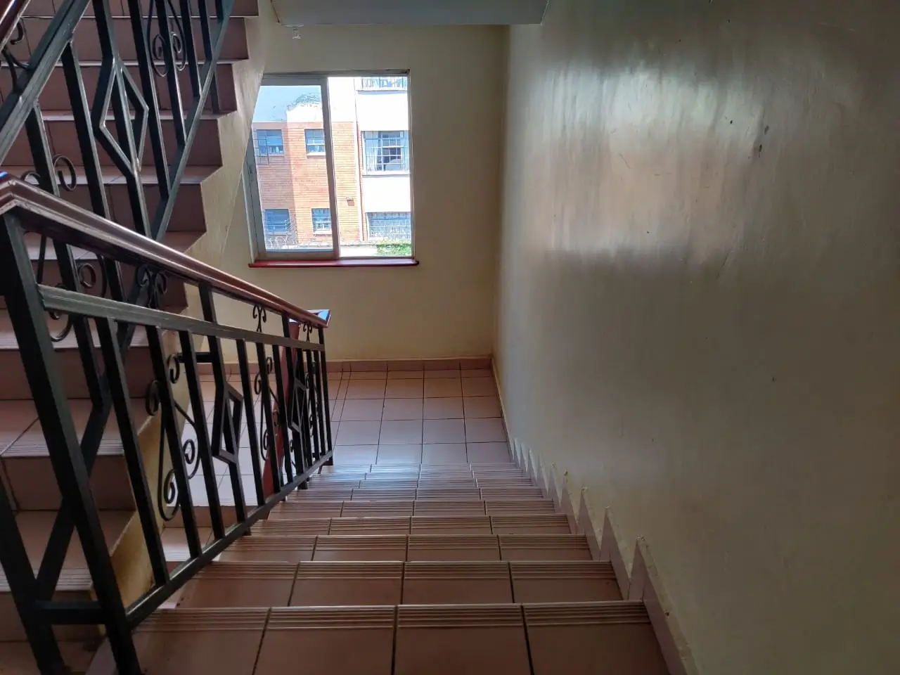 Stairwell landing with terracotta tiles and metal railing