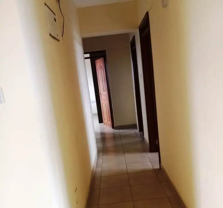 Narrow hallway with cream walls and tile flooring