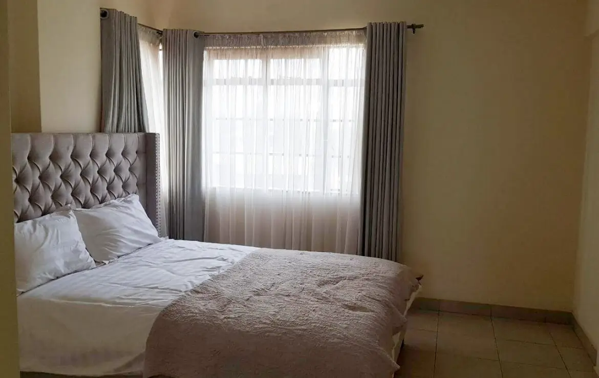 Master bedroom with tufted headboard and garden views