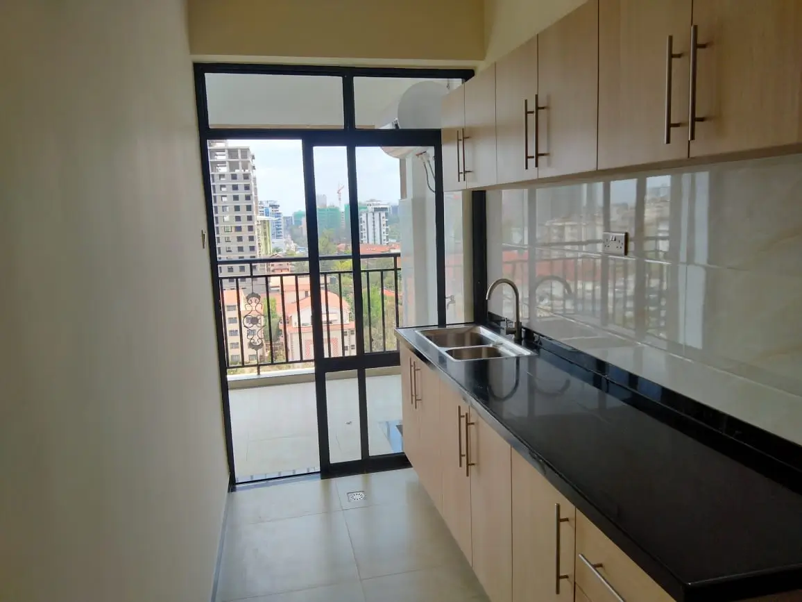 Modern kitchen with black countertops, city skyline views from balcony
