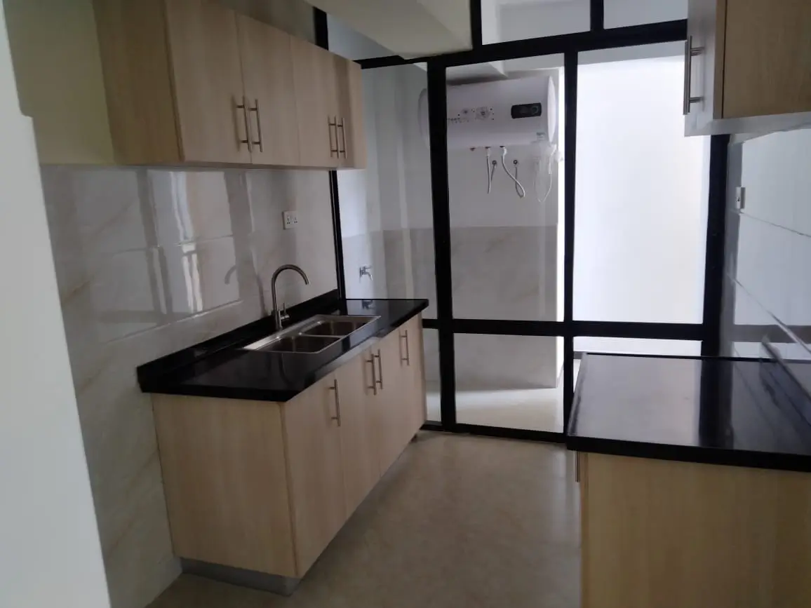 Modern kitchen with wooden cabinets, black countertop, and window
