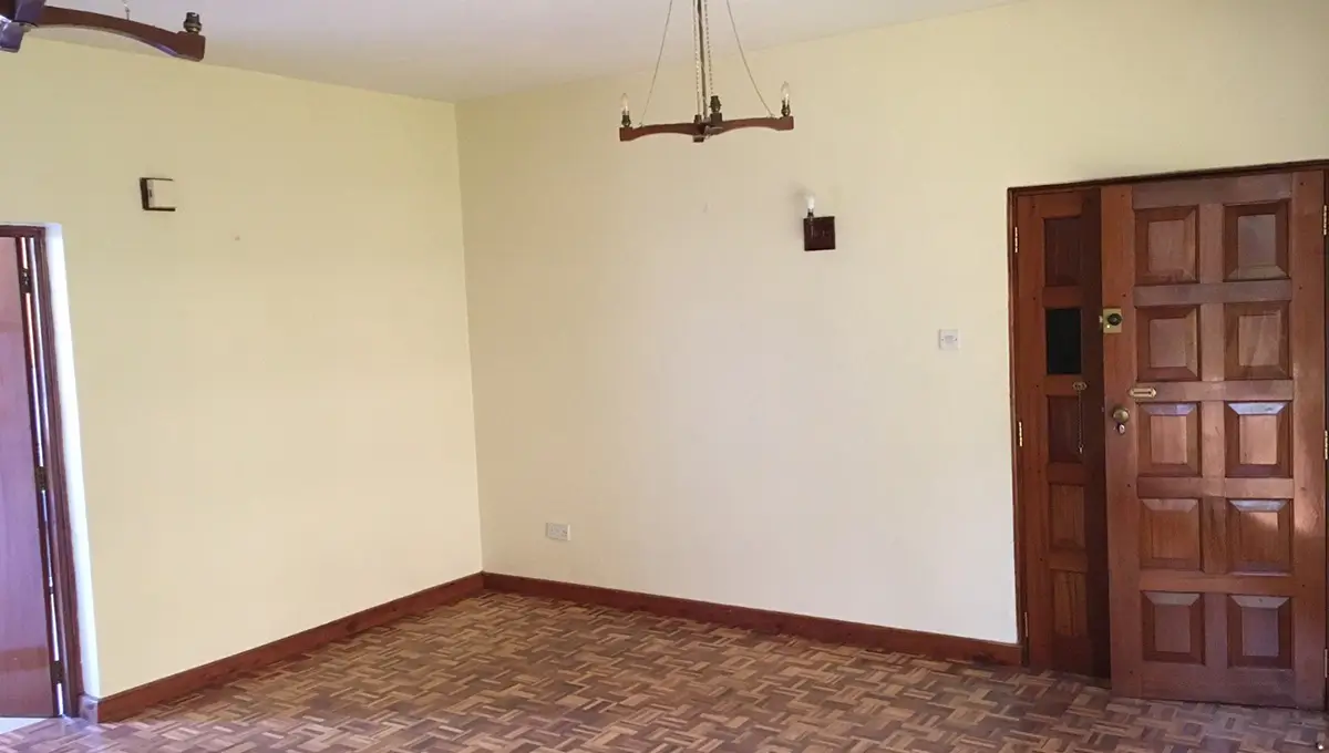 Spacious empty room with wooden door and parquet flooring