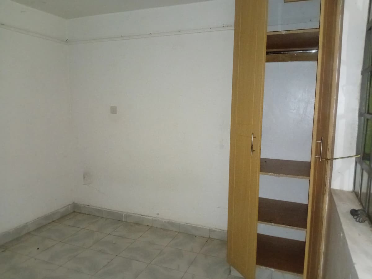 Unfurnished bedroom with wooden wardrobe and concrete flooring