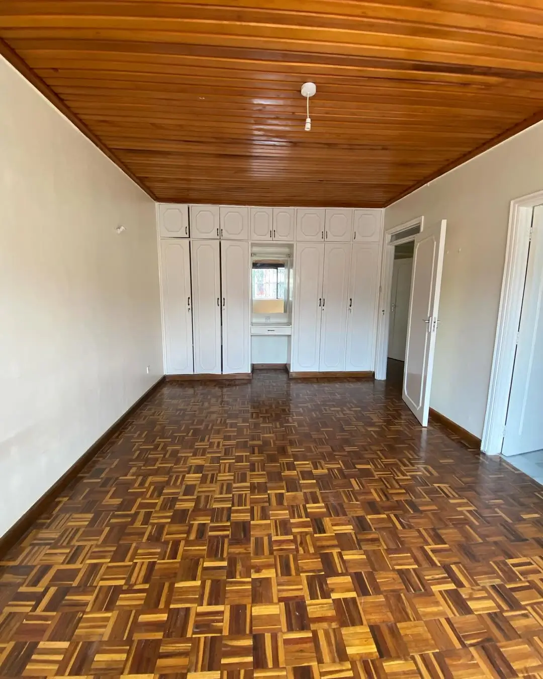 Spacious bedroom with wooden ceiling and built-in wardrobes