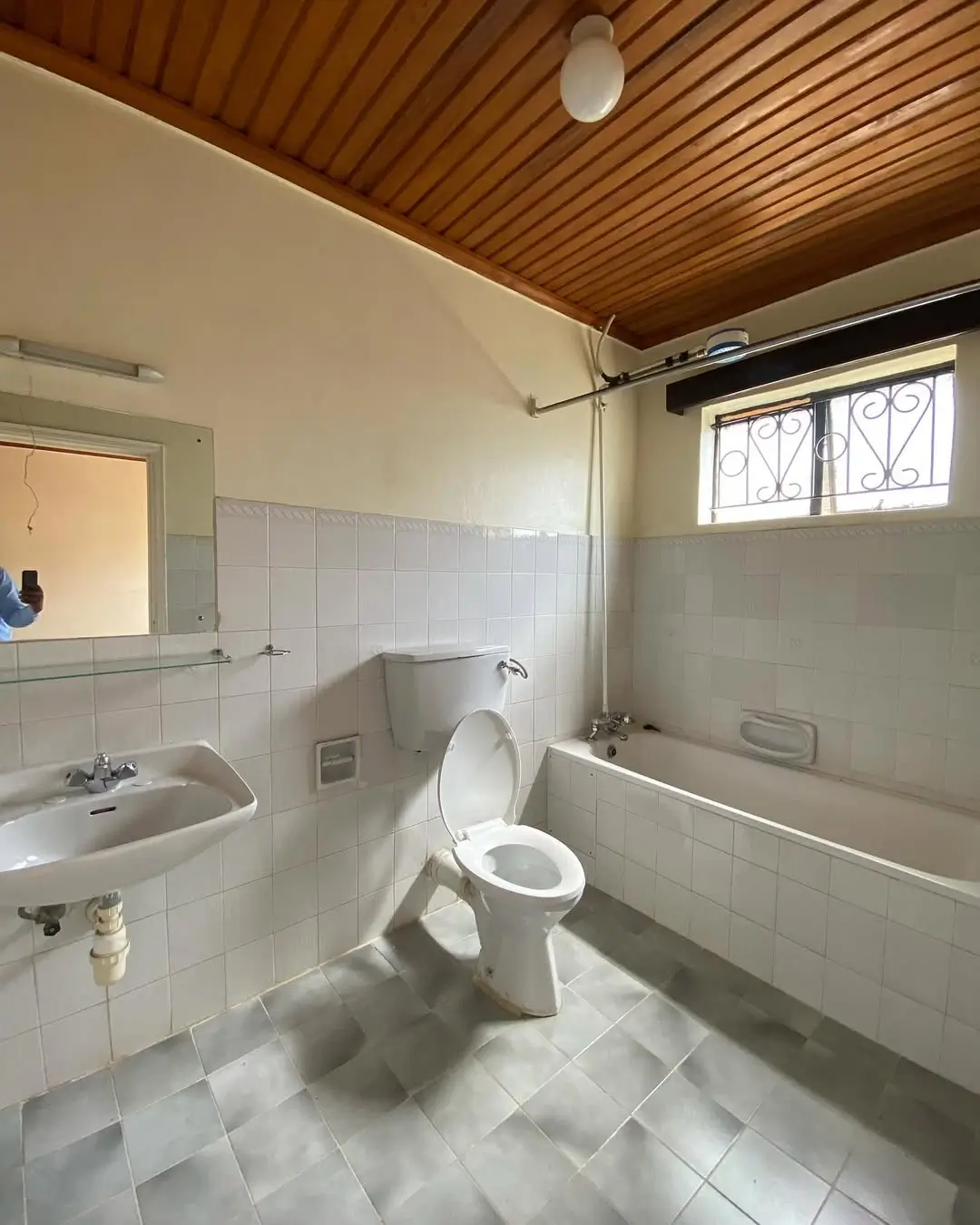 Spacious bathroom with bathtub, toilet, sink, wooden ceiling
